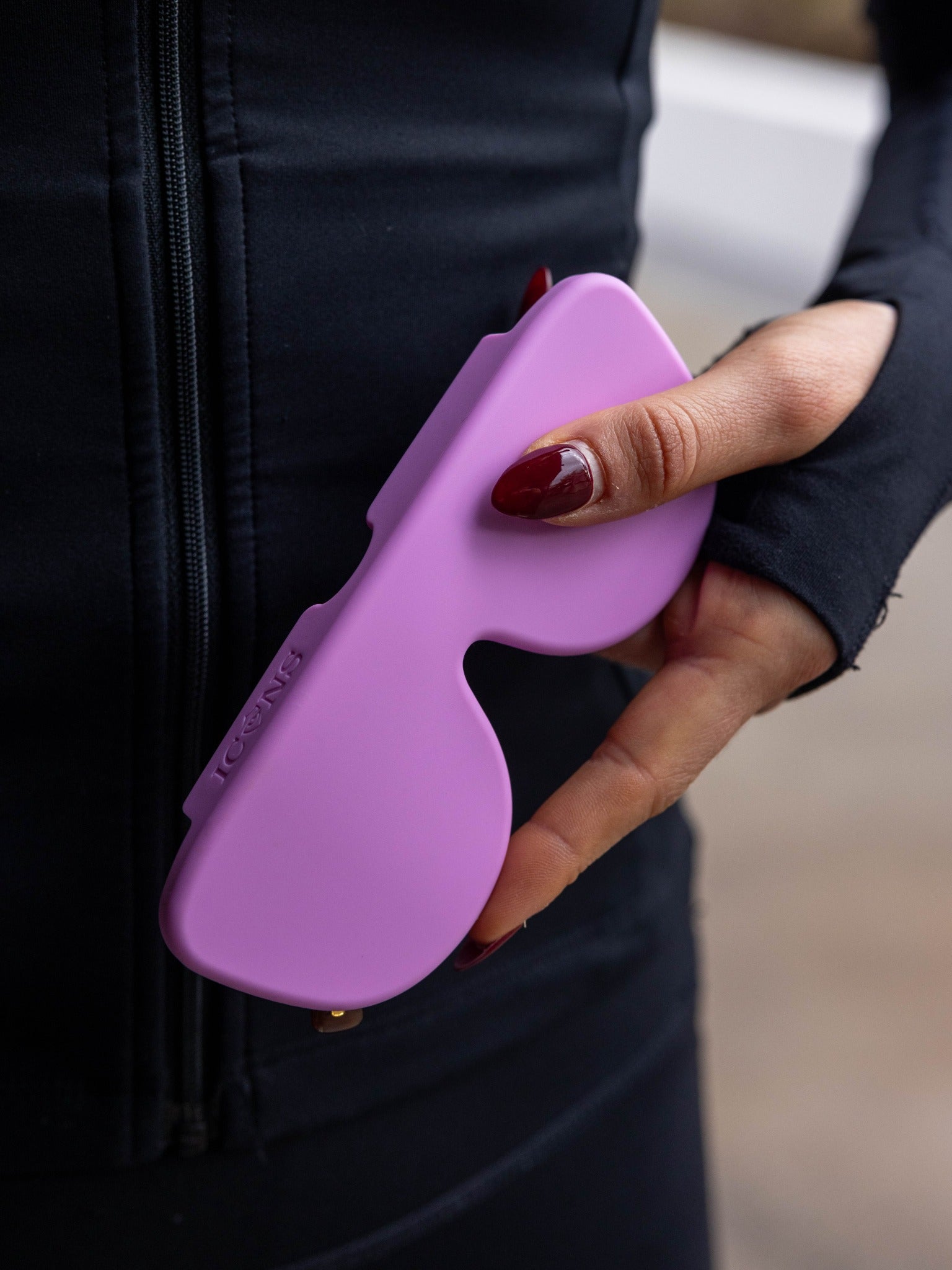 Close-up of the debossed Icons logo on a purple case held in a hand