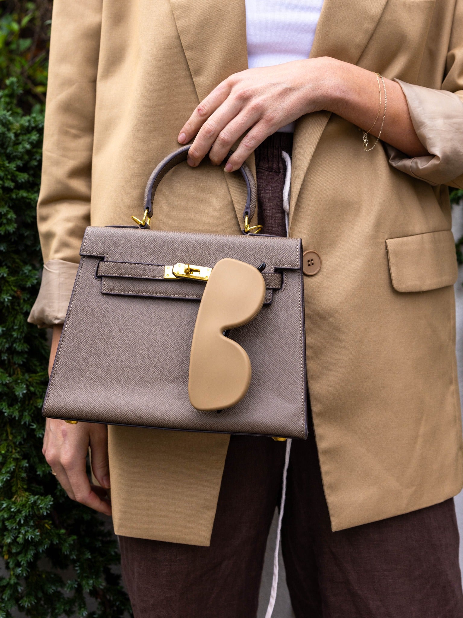 Taupe Icons case hanging from a handbag