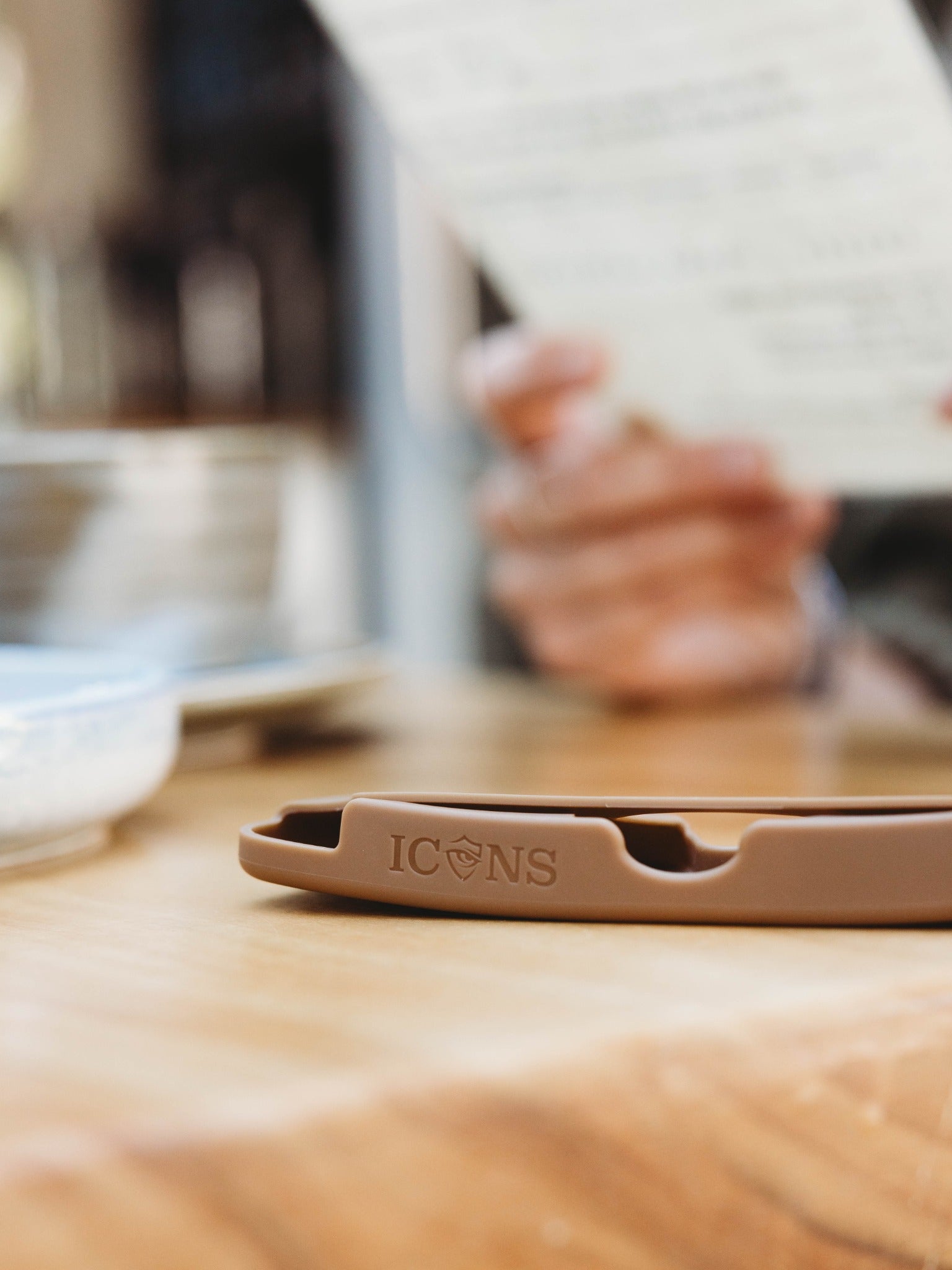Debossed Icons logo on a brown silicone case resting on a café table